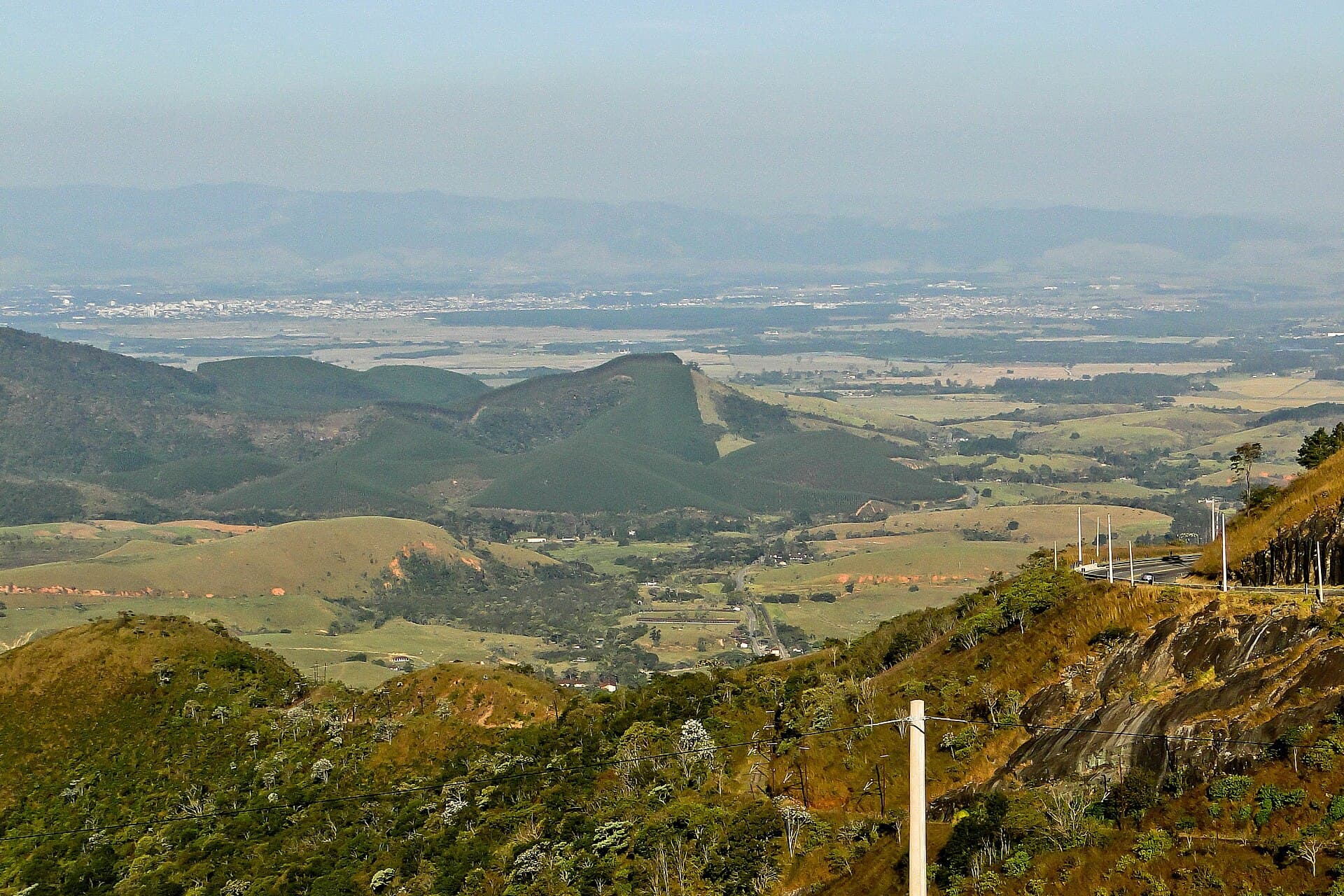 Vale com morros, pastagens e uma estrada vistos de um mirante, em Campos do Jordão