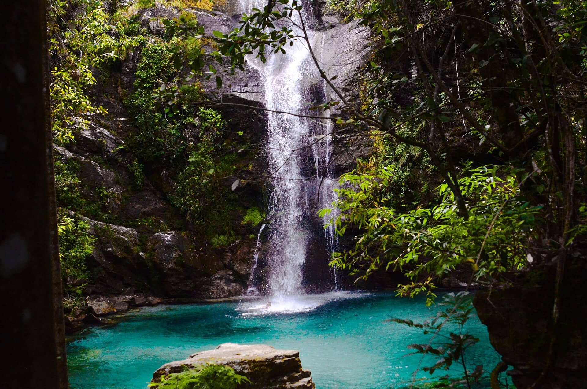 Cachoeira de águas cristalinas caindo em um poço azul-turquesa entre rochas e mata, no território Kalunga, em Goiás