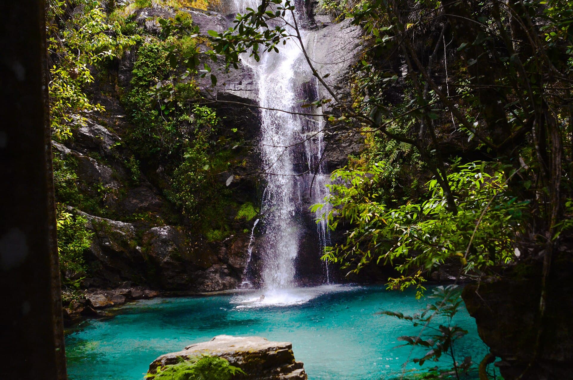 Cachoeira de águas cristalinas caindo em um poço azul-turquesa entre rochas e mata, no território Kalunga, em Goiás