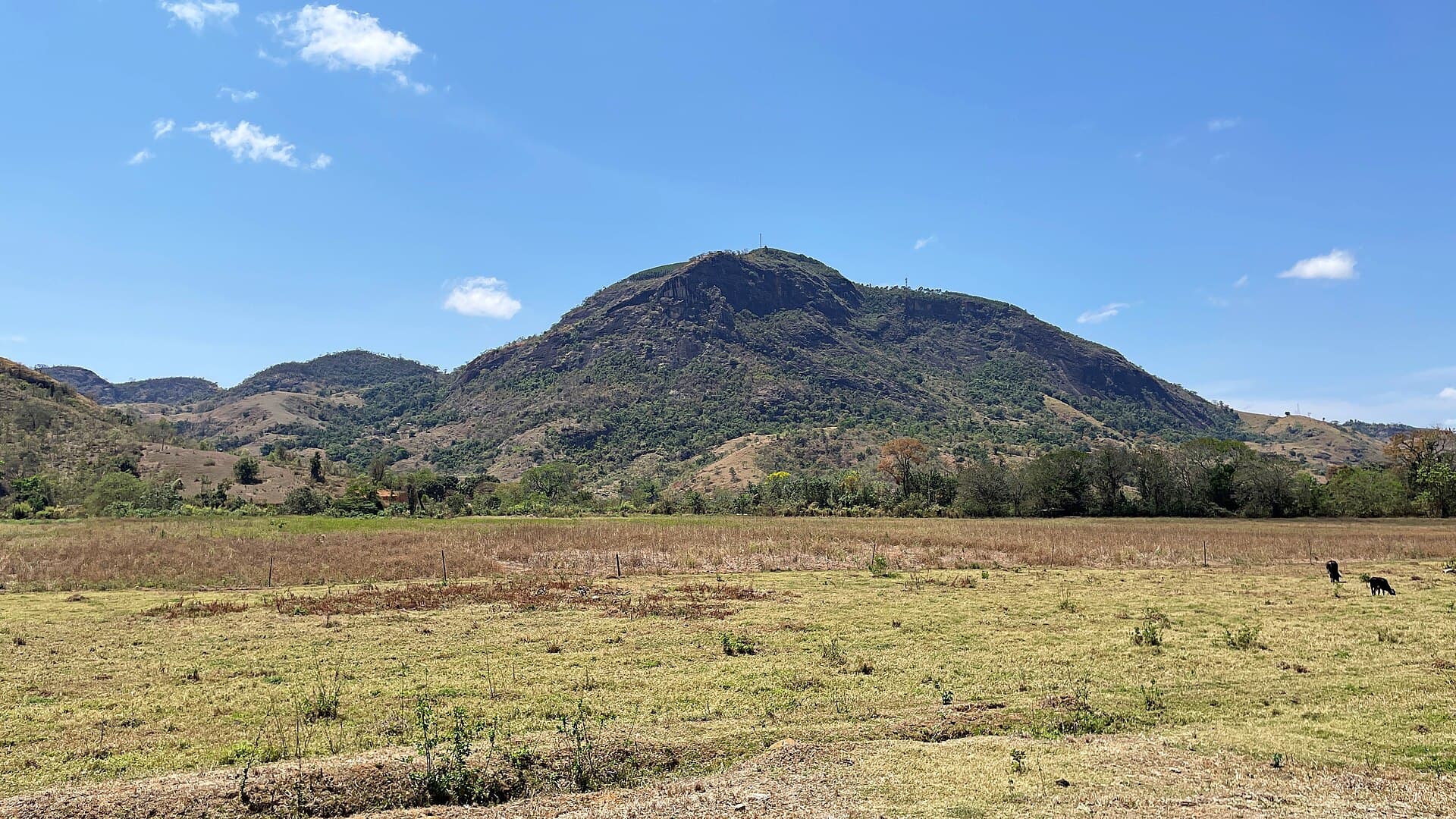 Pastagem em tom seco diante de morro rochoso, em Vargem Alegre, Minas Gerais