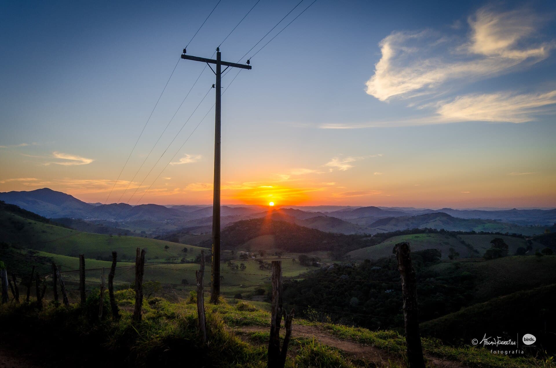 Pôr do sol sobre morros e cercas de fazenda, na Serra da Mantiqueira