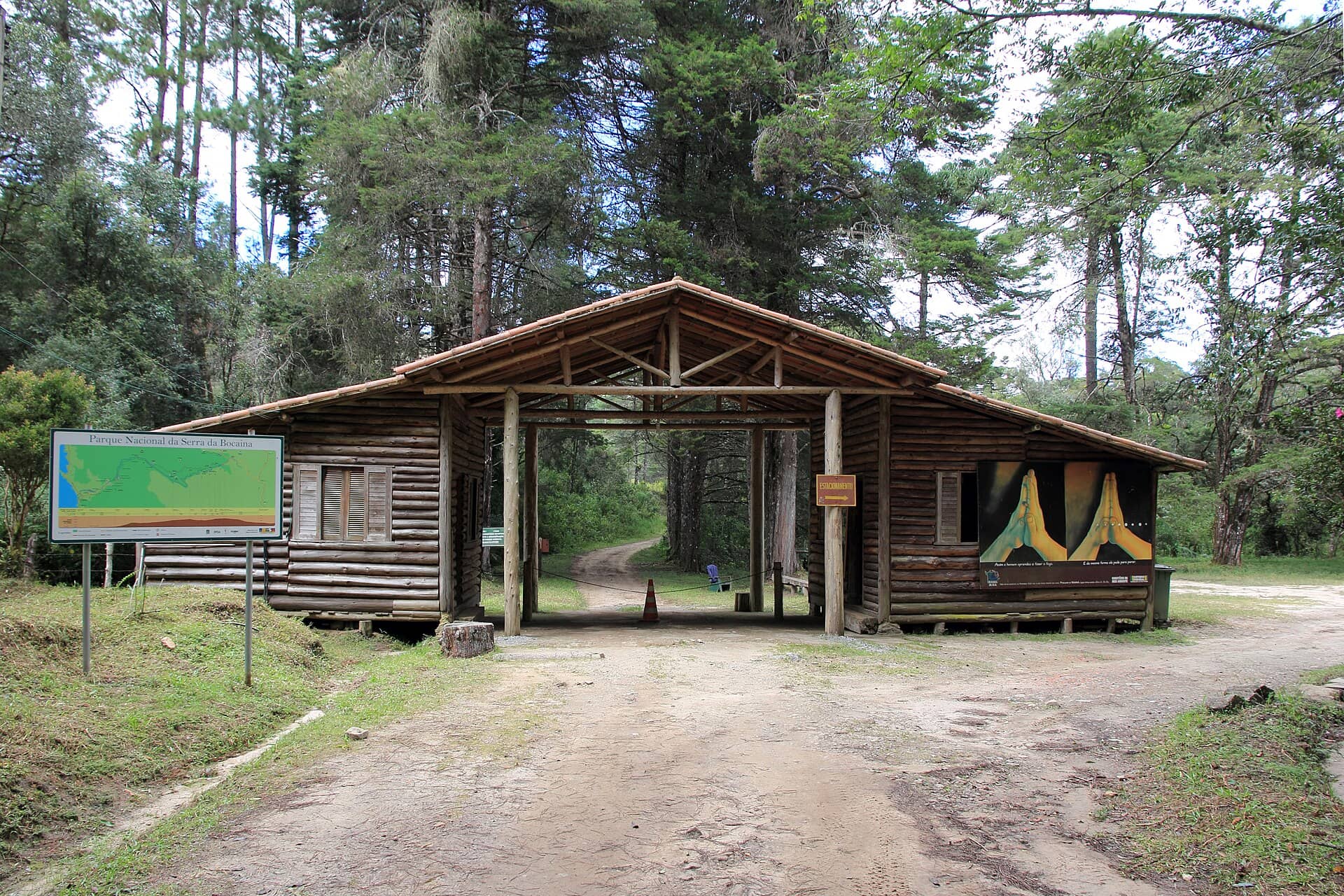 Portaria de madeira rústica na entrada do Parque Nacional da Serra da Bocaina, com mapa e estrada de terra