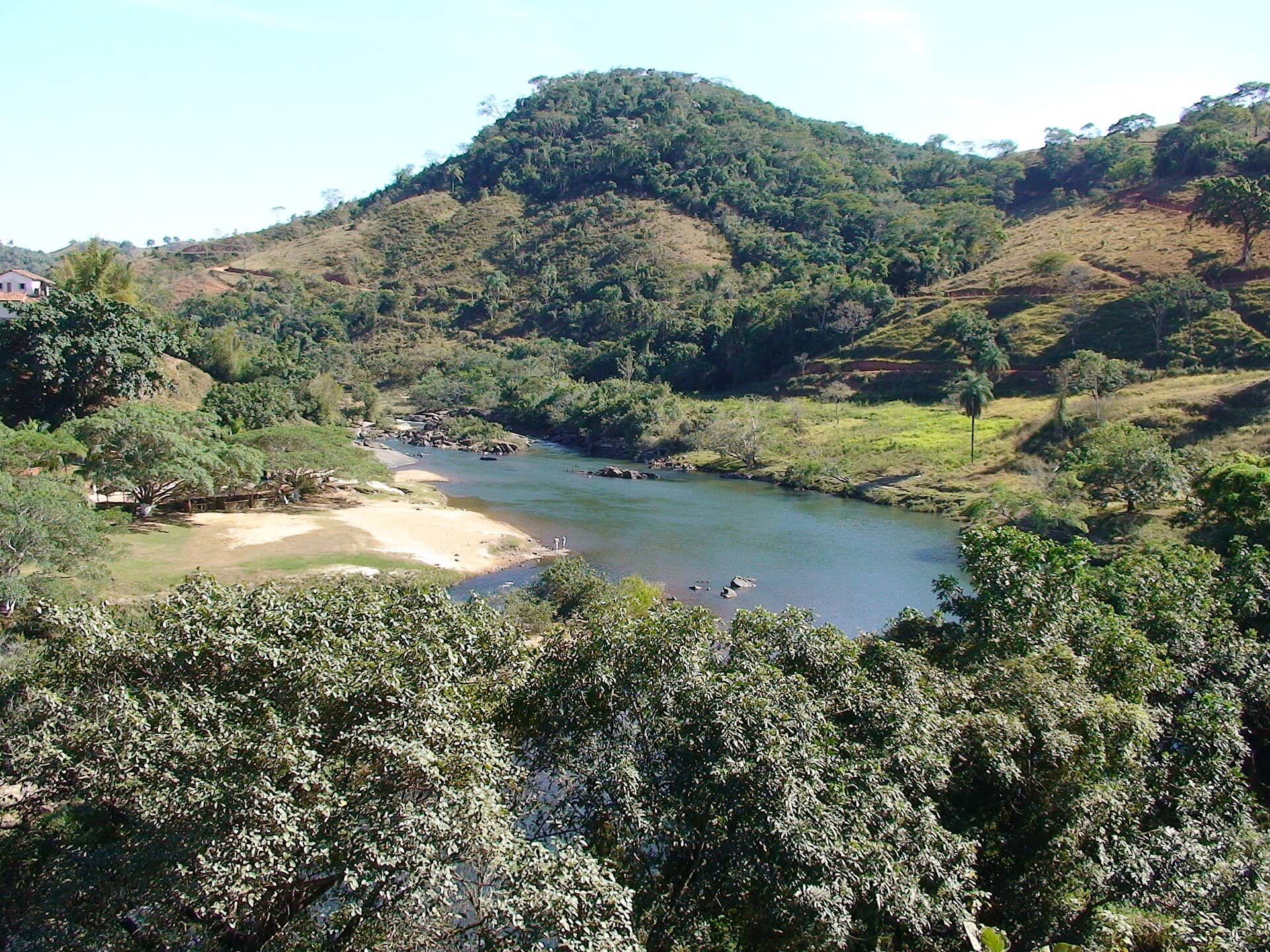 Rio entre morros com mata e pasto, na zona rural de Santo Antônio do Rio Abaixo, Minas Gerais
