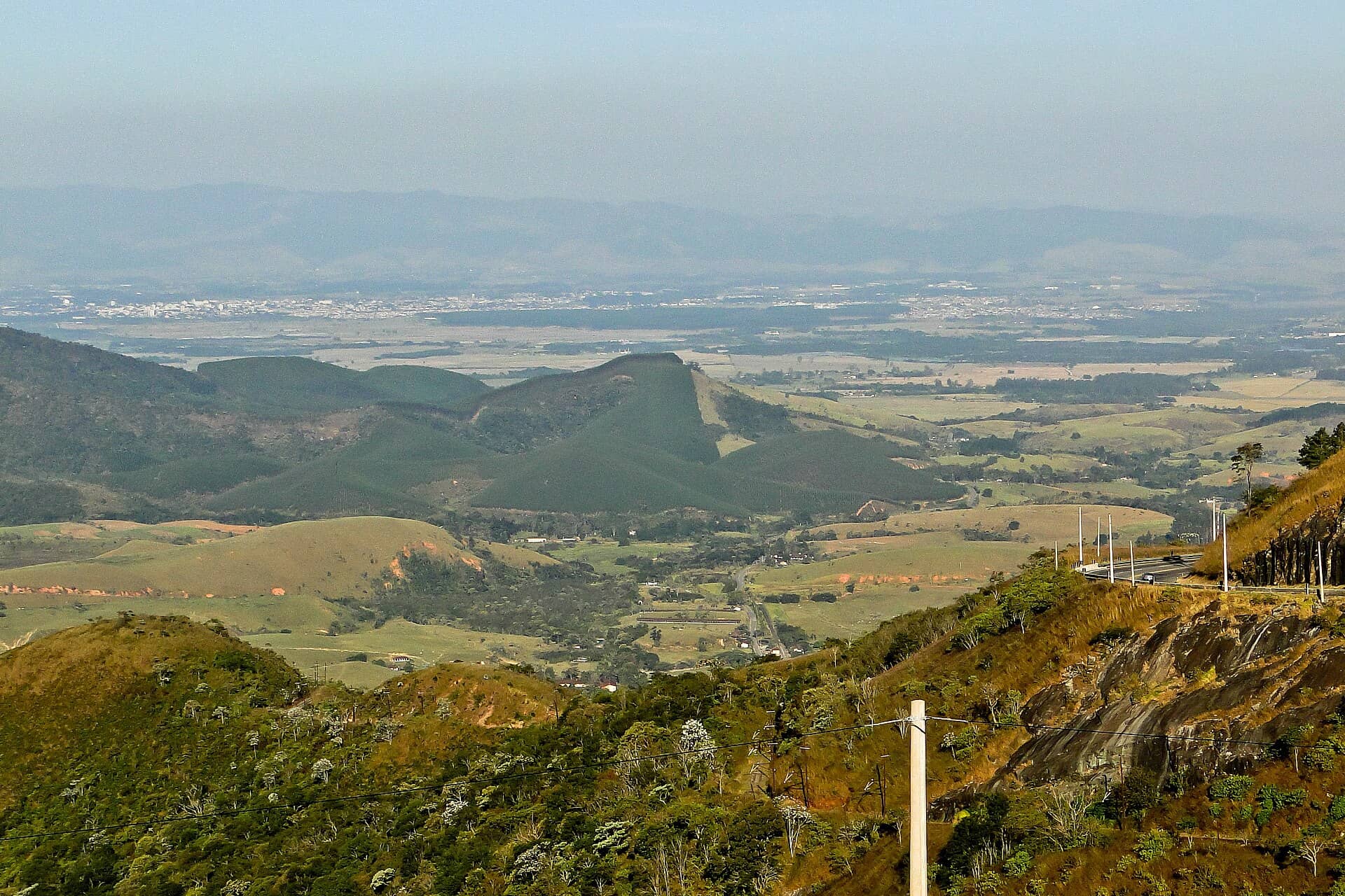 Vale com morros, pastagens e uma estrada vistos de um mirante, em Campos do Jordão