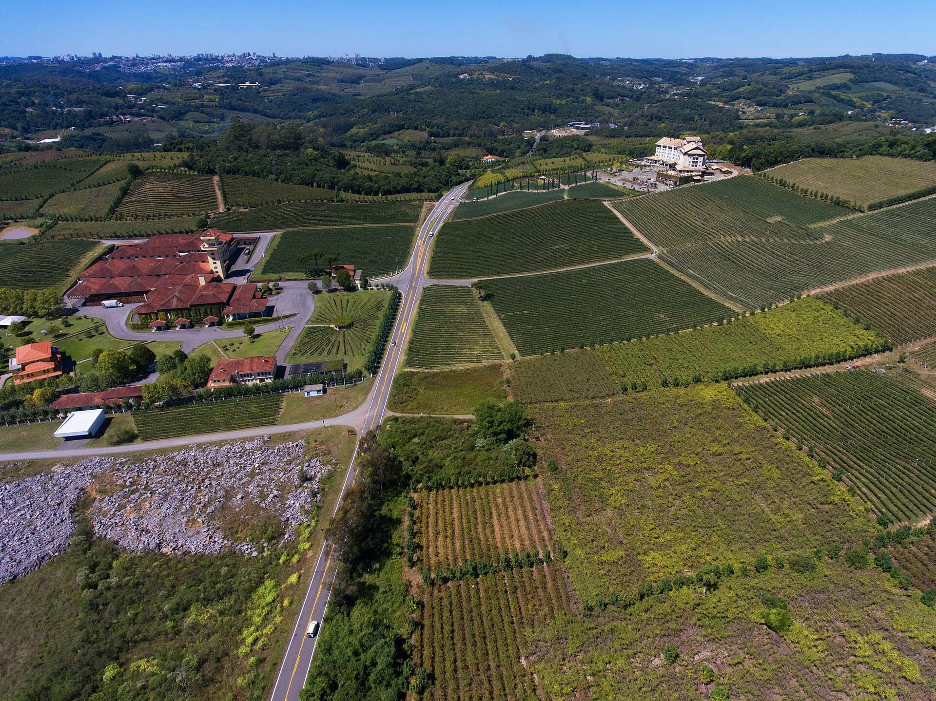 Vista aérea de vinhedos e vinícolas cortados por uma estrada, no Vale dos Vinhedos, em Bento Gonçalves
